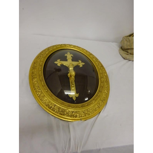 99 - A gilded crucifix in oval framed with curved glass. 57cm x 47cm approx.