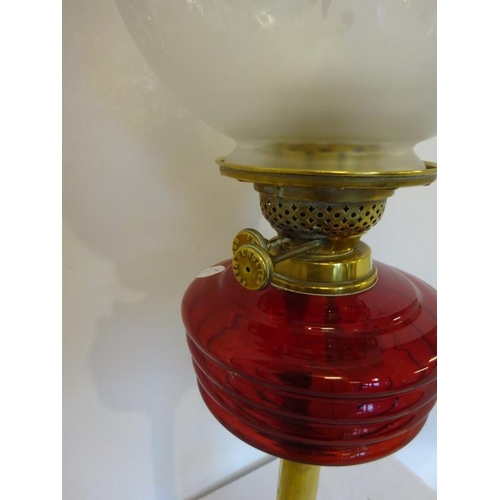 143 - Antique brass column oil lamp with red glass bowl and football shade.