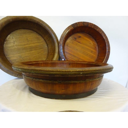 70 - Four large old brass banded timber bowls, one needing attention. Diameter 80cm approx.