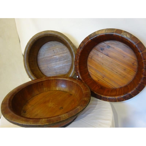 70 - Four large old brass banded timber bowls, one needing attention. Diameter 80cm approx.