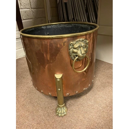 124 - A large antique circular copper and brass log bucket having lion mask handles and raised on claw fee... 