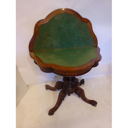 131 - A Victorian figured walnut card table, the shaped folding top on carved and turned column with four ... 