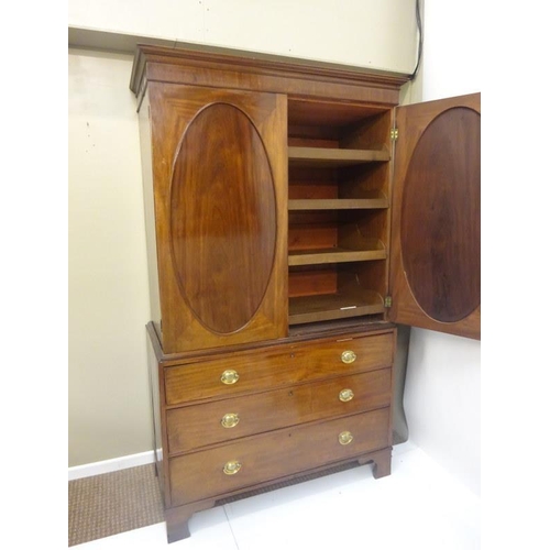 143 - Georgian mahogany linen press, the upper section having two doors with oval panels opening to reveal... 