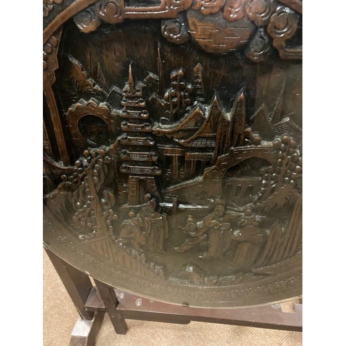 148 - A Japanese hardwood occasional table, the circular tilt top with carved figures and pagodas in a lan... 