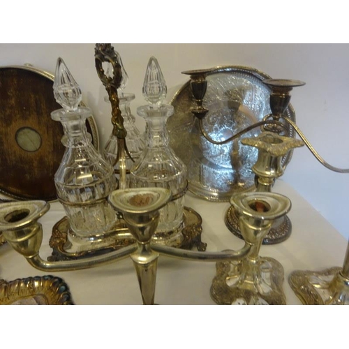 187 - A mixed lot of plated ware to include a decanter set, candleabra, table brush and crumb tray, etc.