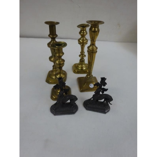 2 - Four old brass candlesticks and two greyhound fireplace ornaments (possibly lacking glass flutes). (... 