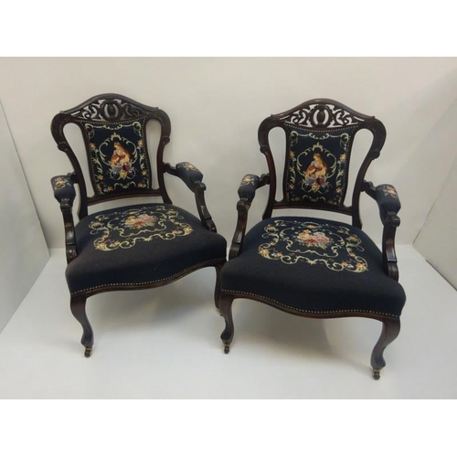 308 - A pair of late 19th century carved mahogany open arm drawing room chairs with needlework upholstery.