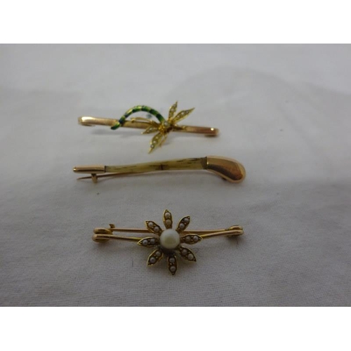 297 - Three gold brooches - one dragonfly, one hockey stick and a pearl brooch.