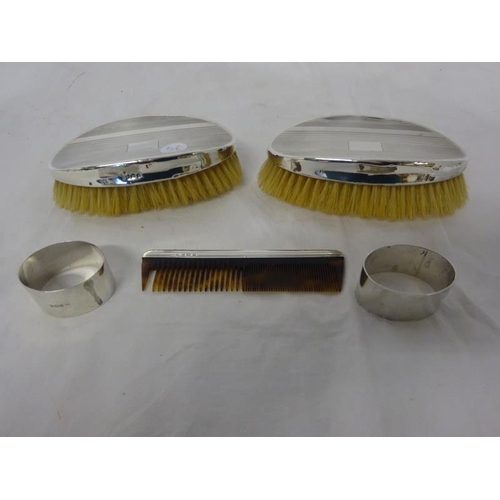 320 - Two silver brushes, silver comb and two napkin rings.