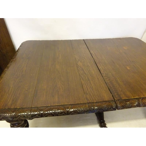 106 - Victorian oak dining table having two spare leaves and raised on five legs with harp decoration.