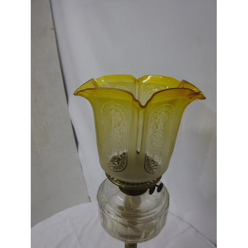 63 - Antique brass corinthian column oil lamp with clear glass bowl and old yellow shade.