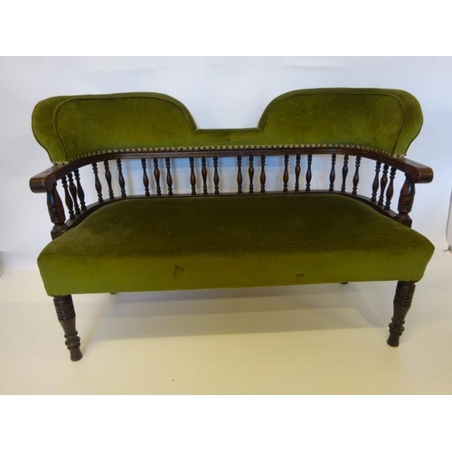 69 - An Edwardian oak framed settee having shaped back with spindle decoration and raised on turned legs.... 