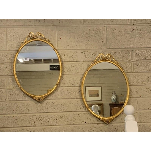 132 - A pair of antique neat sized gilt wood wall mirrors with ribbon decoration. H. 60cm, W. 43cm.