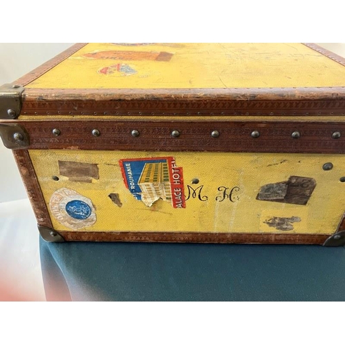 236 - Louis Vuitton suitcase, leather trimmed and studded and covered with travel stickers and monogrammed... 