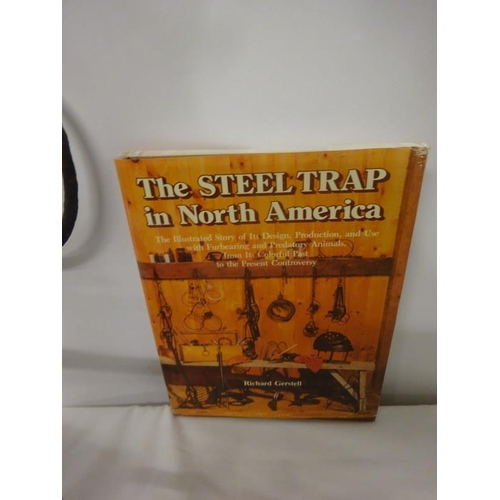 245 - A rare antique hand forged metal trap together with a book, The Steel Trap in North America. (2)