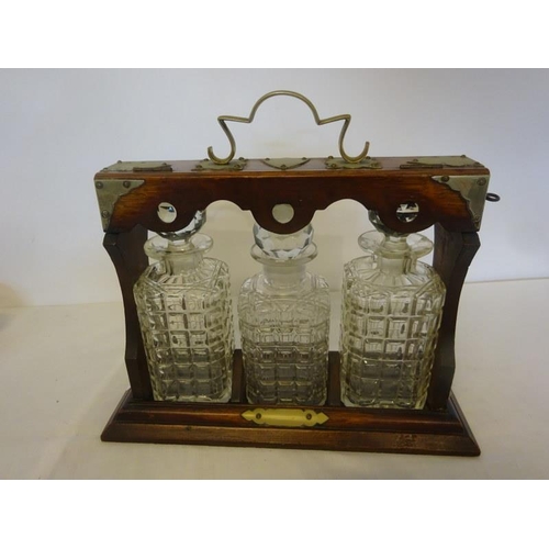 318 - Victorian oak cased tantalus with 3 matching decanters and stoppers.