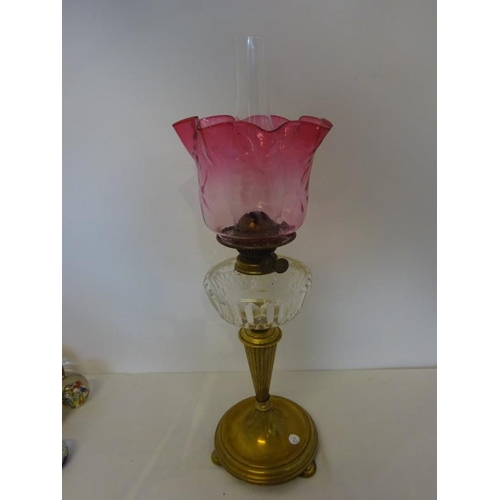 323 - Antique brass column oil lamp having clear glass bowl and red glass shade in fine condition.