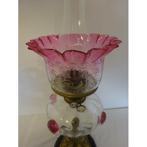 326 - Antique brass column oil lamp having clear glass bowl with tear drop decoration and red glass shade ... 