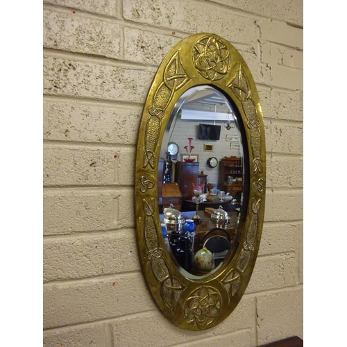 366 - An Arts & Crafts brass framed oval wall mirror. L. 85cm, W. 40cm.