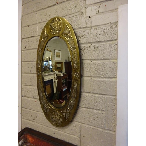 366 - An Arts & Crafts brass framed oval wall mirror. L. 85cm, W. 40cm.