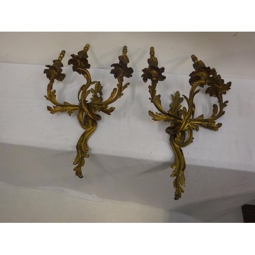 60 - A pair of antique gilt brass three branch candle sconces.