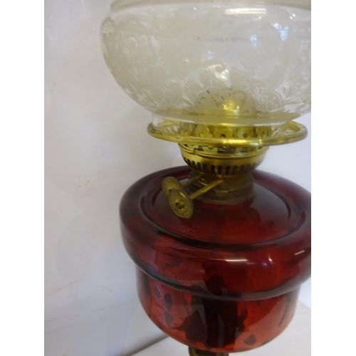 93 - Antique brass oil lamp with red glass bowl and decorative shade.