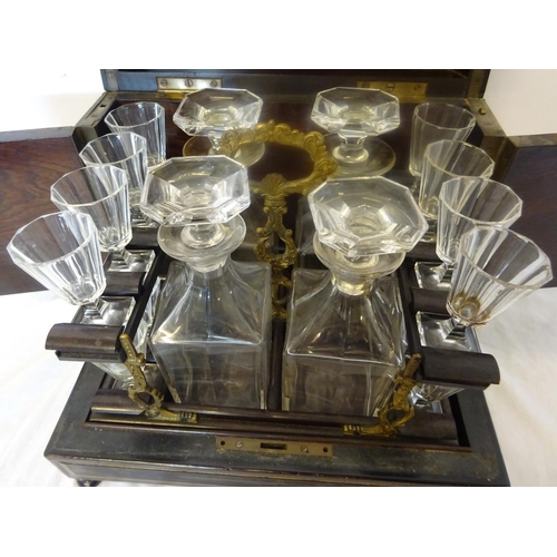 97 - Antique brass inlaid decanter box fitted with four decanters and fourteen small glasses (2 missing).