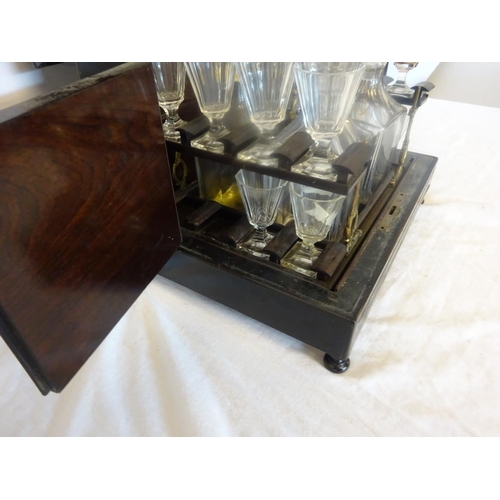 97 - Antique brass inlaid decanter box fitted with four decanters and fourteen small glasses (2 missing).