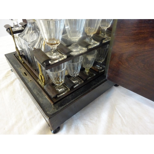 97 - Antique brass inlaid decanter box fitted with four decanters and fourteen small glasses (2 missing).