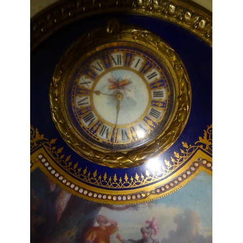 79 - A fine antique decorative French table clock housed in oval gilt brass frame with serves porcelain p... 