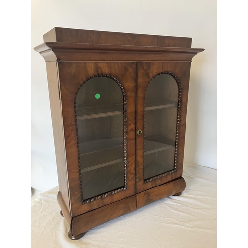 155 - A neat size mid 19th century table top mahogany cabinet having two arched doors with glass panels, t... 