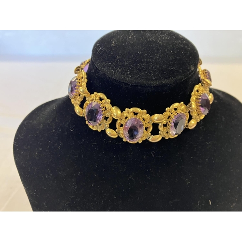 211 - A decorative 9ct gold bracelet with 9 amethyst stones. Clasp needs attention. Length 20cm approx.