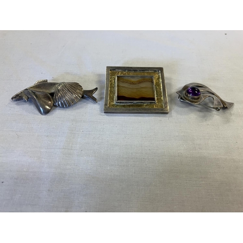 218 - Silver landscape brooch together with a silver fish and shell brooch and a brooch with colour stone.... 