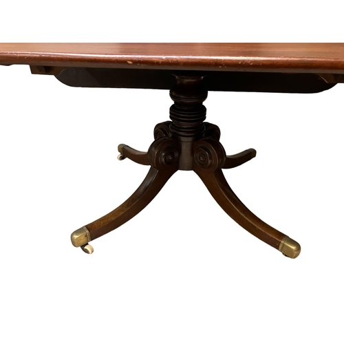 323 - A 19th century mahogany drop leaf dining table raised on centre column with 4 splay feet and brass t... 