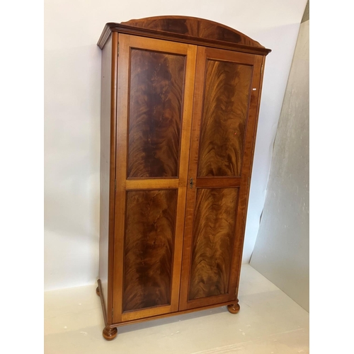 39 - An excellent quality mahogany wardrobe having shaped cornice over two long panel doors and raised on... 