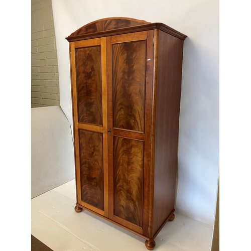 39 - An excellent quality mahogany wardrobe having shaped cornice over two long panel doors and raised on... 