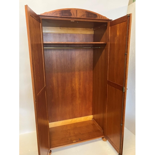 39 - An excellent quality mahogany wardrobe having shaped cornice over two long panel doors and raised on... 