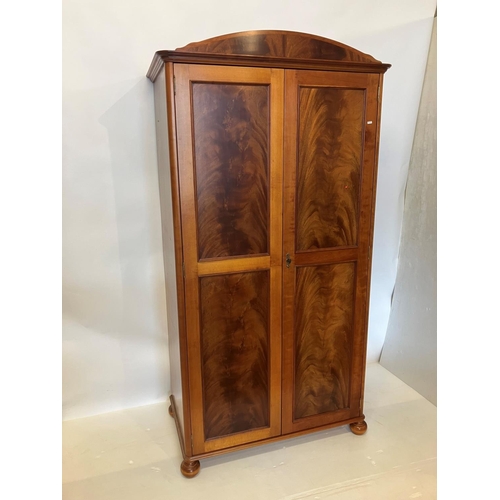 39 - An excellent quality mahogany wardrobe having shaped cornice over two long panel doors and raised on... 