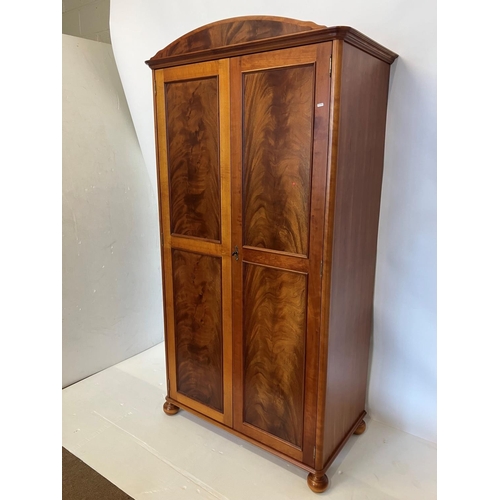 39 - An excellent quality mahogany wardrobe having shaped cornice over two long panel doors and raised on... 