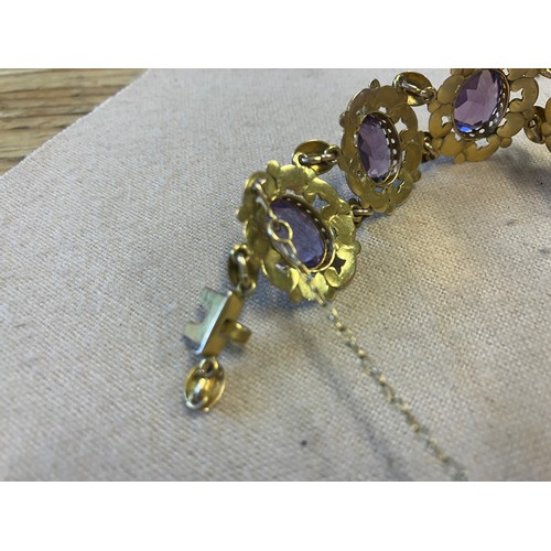 211 - A decorative 9ct gold bracelet with 9 amethyst stones. Clasp needs attention. Length 20cm approx.