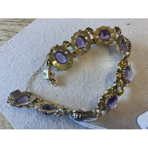 211 - A decorative 9ct gold bracelet with 9 amethyst stones. Clasp needs attention. Length 20cm approx.