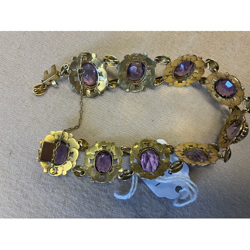 211 - A decorative 9ct gold bracelet with 9 amethyst stones. Clasp needs attention. Length 20cm approx.