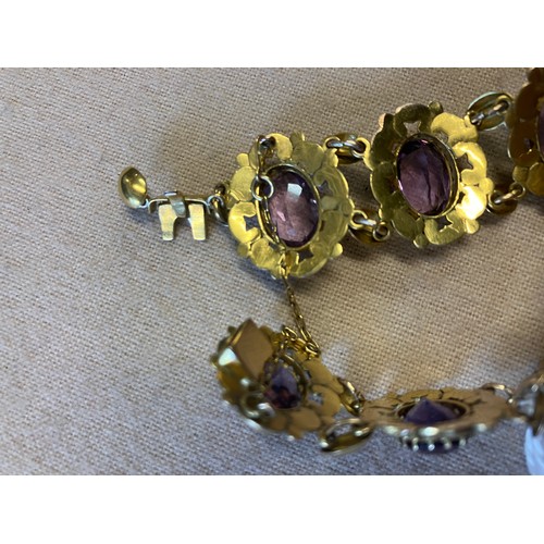 211 - A decorative 9ct gold bracelet with 9 amethyst stones. Clasp needs attention. Length 20cm approx.