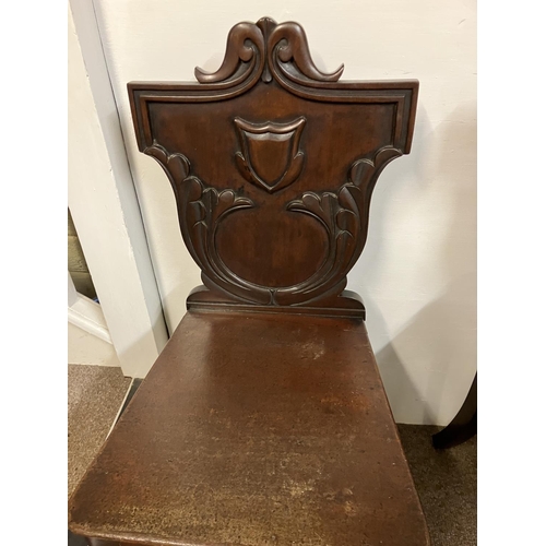 102 - A pair of antique mahogany hall chairs having shaped backs with carved decoration and raised on tuli... 