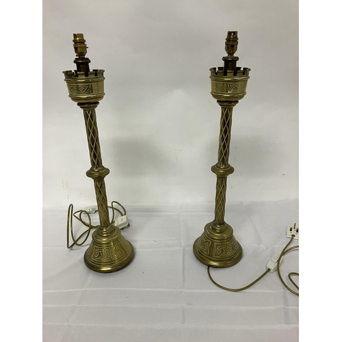 143 - A pair of antique tall brass candlesticks, electrified with Celtic motiffs. H. 70cm without shades.