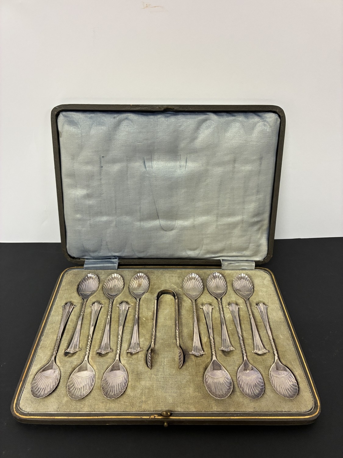 A cased set of 12 decorative teaspoons and sugar tongs.