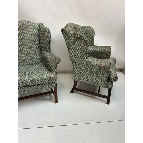 A pair of Georgian style wing back armchairs raised on square legs with ...