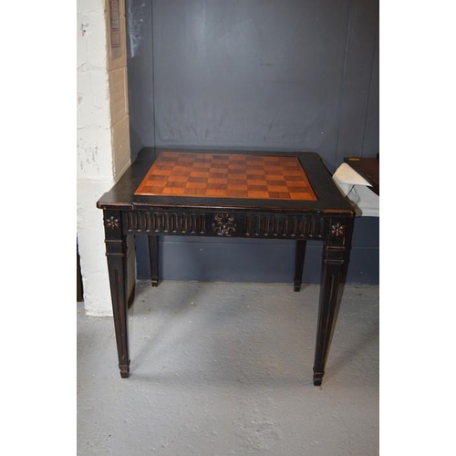 478 - An Empire style ebonised games table, with rotating marquetry chess top, raised on square tapered le... 