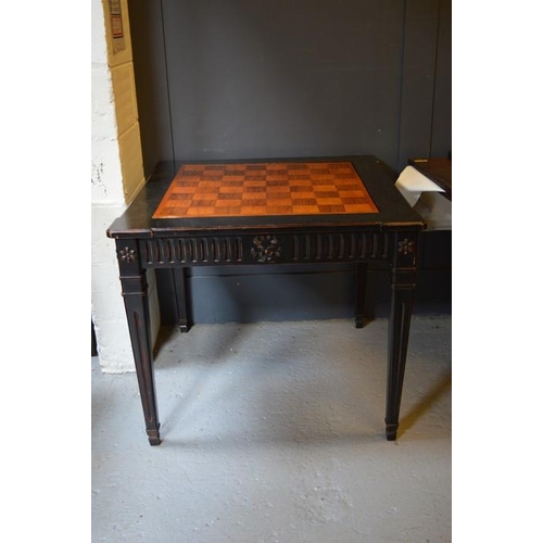 478 - An Empire style ebonised games table, with rotating marquetry chess top, raised on square tapered le... 