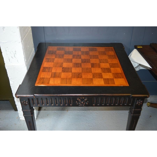 478 - An Empire style ebonised games table, with rotating marquetry chess top, raised on square tapered le... 